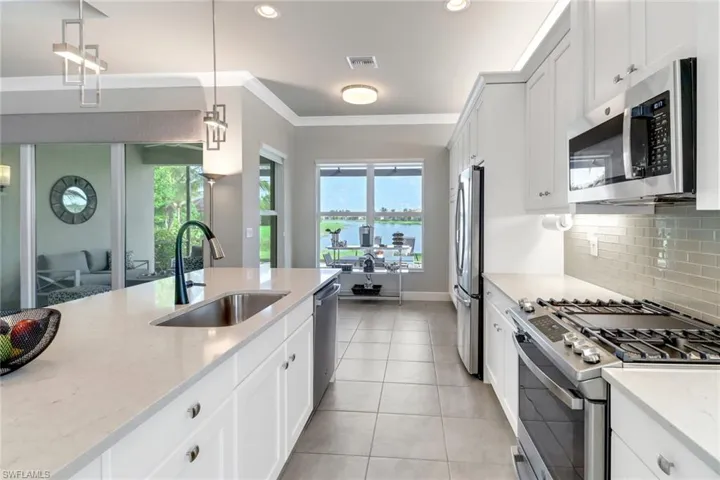 Kitchen with appliances with stainless steel finishes, pendant lighting, white cabinetry, and sink