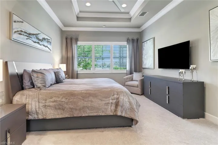 Bedroom featuring light colored carpet and a raised ceiling