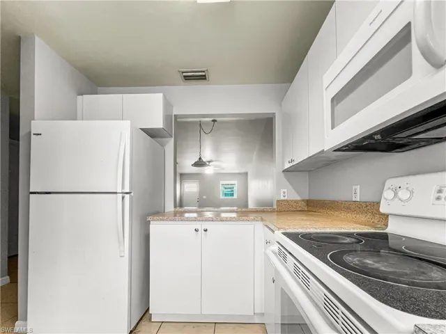 Kitchen featuring white cabinetry, light-colored countertops, white refrigerator, white electric range, and a white microwave