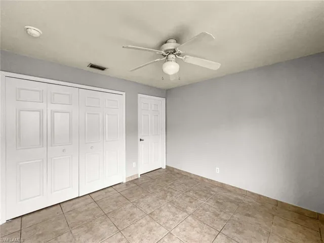 Room featuring neutral-toned tile flooring, light gray walls, and white trim