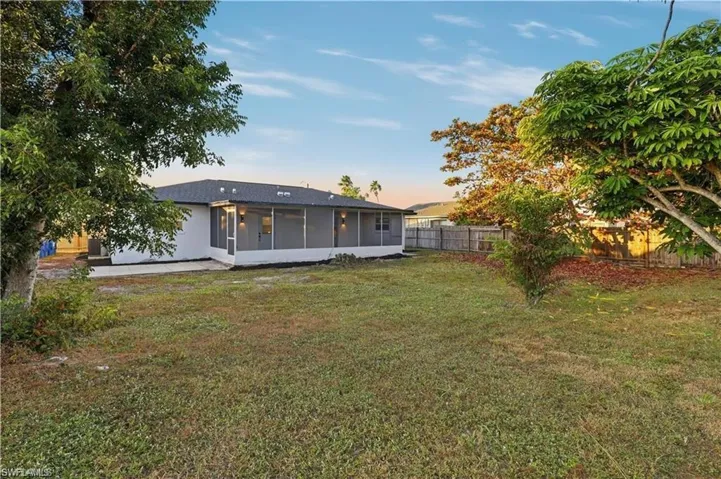 Back of house with a fenced backyard, a sunroom, and a patio