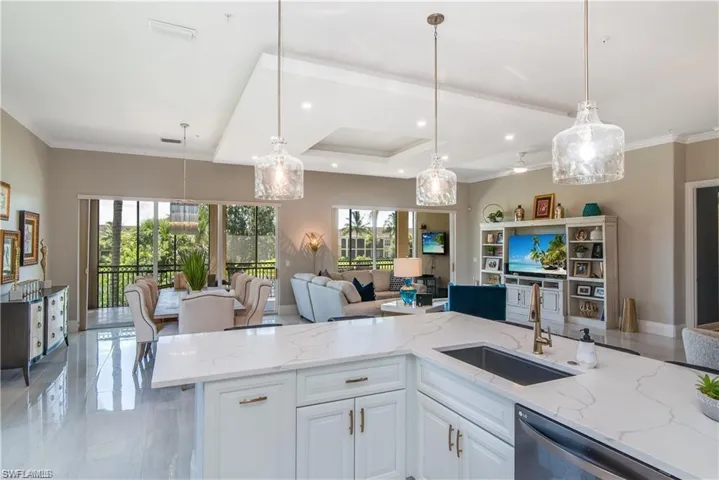 Kitchen featuring light stone countertops, open floor plan, white cabinets, decorative light fixtures, and ornamental molding