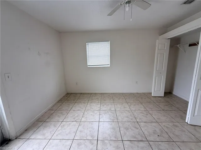 Square ceramic tile flooring, ceiling fan with integrated lighting, and a closet with bifold doors