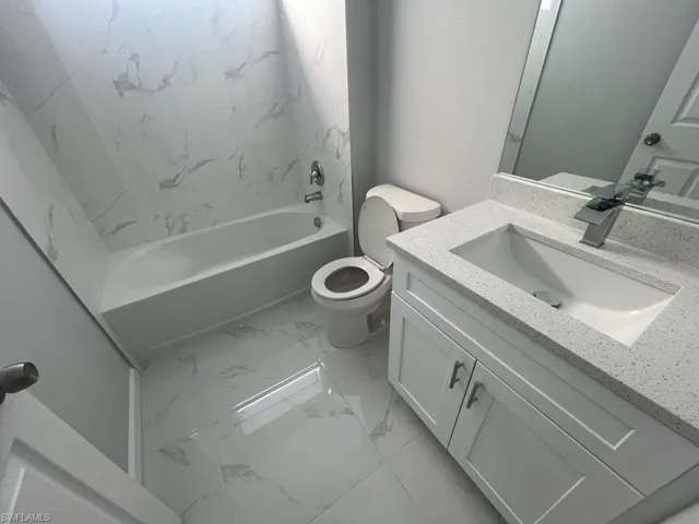 Full bathroom featuring tiled shower / bath, vanity, and toilet