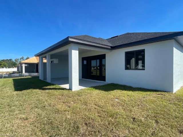 Rear view of property with a lawn and a patio area