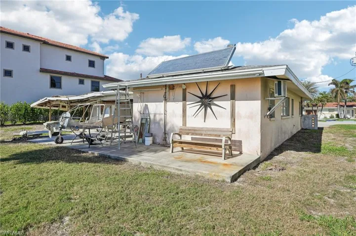 Rear view of house with solar panels, a yard, and a patio