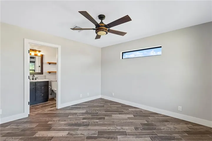 Unfurnished bedroom featuring ceiling fan, dark hardwood / wood-style flooring, ensuite bathroom, and sink