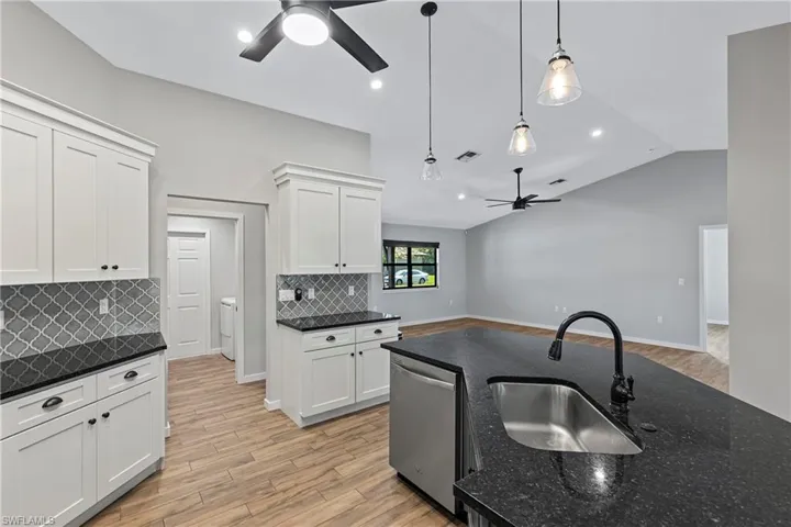 Kitchen featuring dishwasher, sink, pendant lighting, light hardwood / wood-style floors, and white cabinets