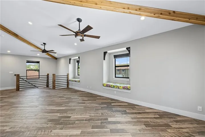 Unfurnished room with lofted ceiling with beams, ceiling fan, and wood-type flooring