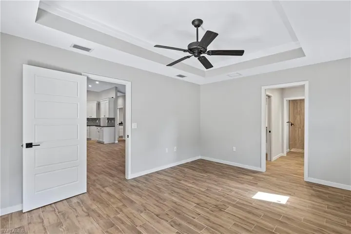 Spare room featuring light wood-type flooring, a raised ceiling, and ceiling fan