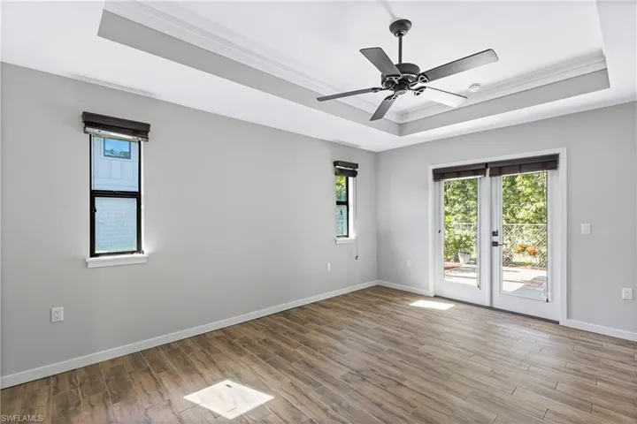 Unfurnished room featuring wood-type flooring, a tray ceiling, ceiling fan, and crown molding
