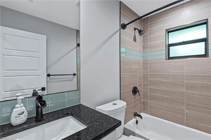 Full bathroom with vanity, tiled shower / bath combo, and toilet