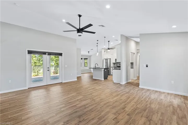 Unfurnished living room with ceiling fan, light hardwood / wood-style floors, sink, and french doors