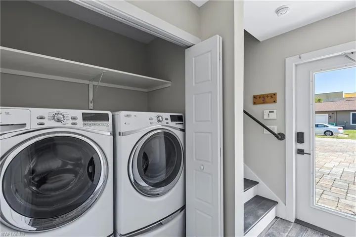Clothes washing area featuring washing machine and dryer and light hardwood / wood-style flooring