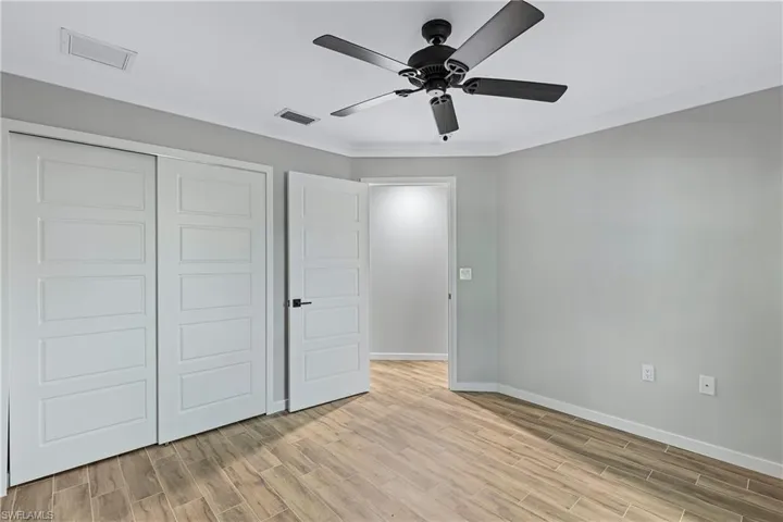 Unfurnished bedroom with ceiling fan, a closet, crown molding, and light hardwood / wood-style flooring