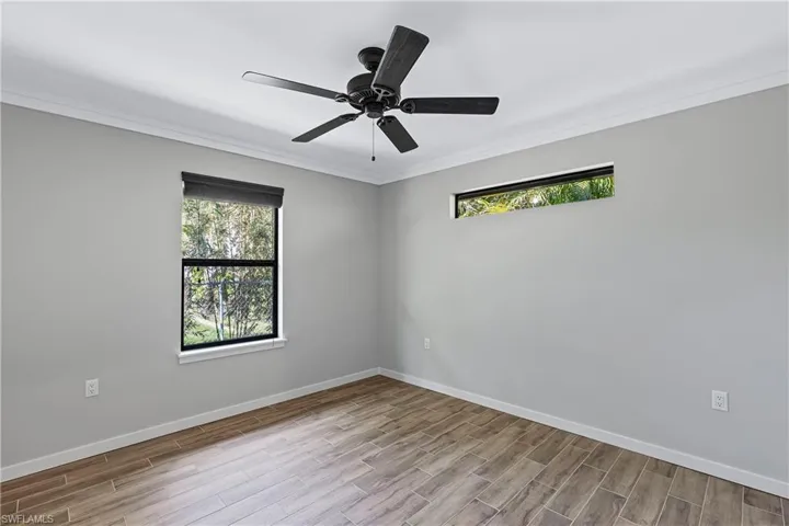 Empty room with light hardwood / wood-style flooring, plenty of natural light, crown molding, and ceiling fan