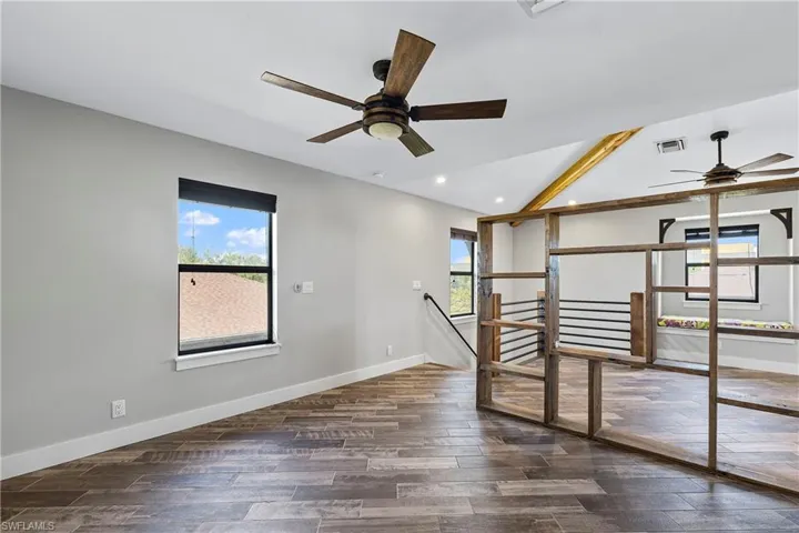 Empty room with plenty of natural light, dark hardwood / wood-style flooring, and lofted ceiling