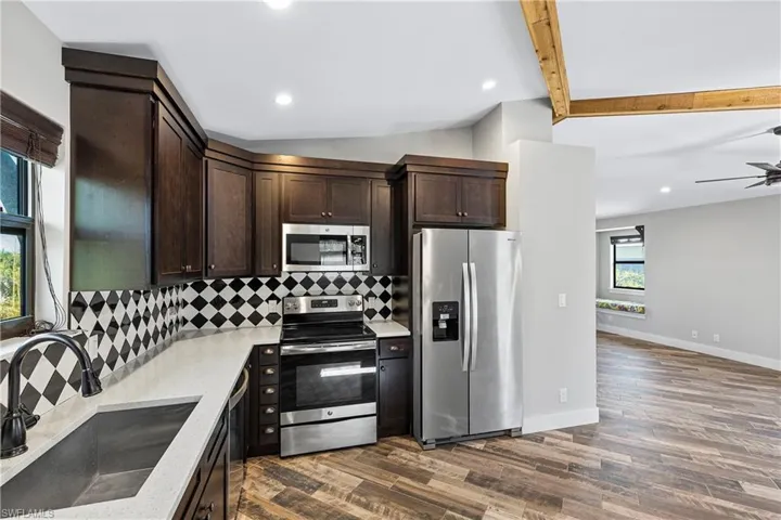 Kitchen with appliances with stainless steel finishes, lofted ceiling with beams, a wealth of natural light, and sink