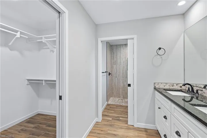 Bathroom with a tile shower, vanity, and hardwood / wood-style flooring