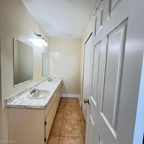 Bathroom featuring a double vanity with integrated sinks, laminate countertops, and tile flooring