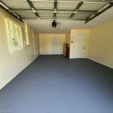 Spacious garage with a finished gray floor, multiple entry doors, and an automatic garage door opener