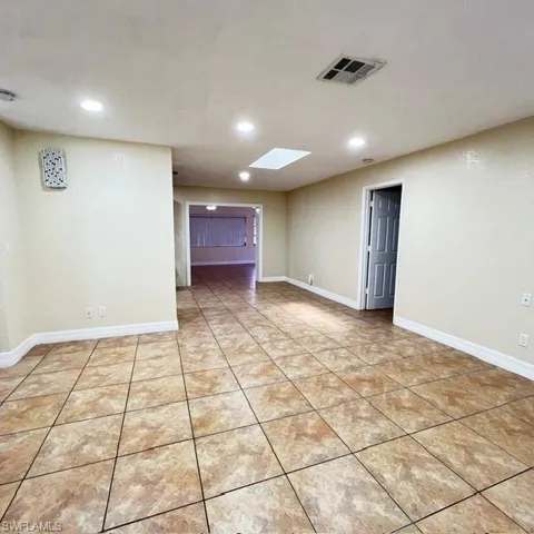 Spacious room featuring neutral-toned tile flooring, recessed lighting, and a skylight