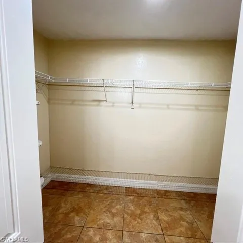 Spacious walk-in closet featuring wire shelving, hanging rods, and patterned tile flooring