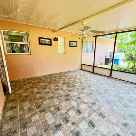 Screened porch featuring multi-toned square tile flooring and a ceiling fan
