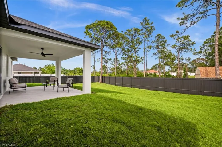 The property features an extensive backyard with a well-maintained lawn, a covered patio, and a privacy fence