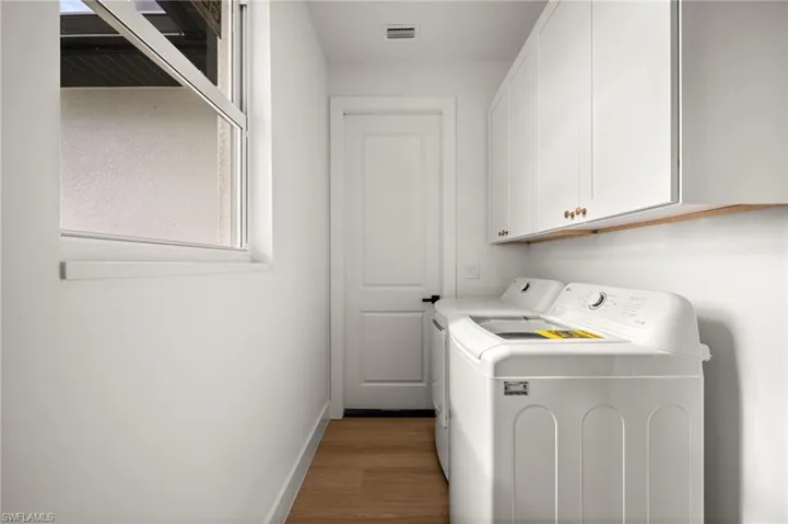 Utility room featuring a window, white cabinetry, and light-toned wood style flooring