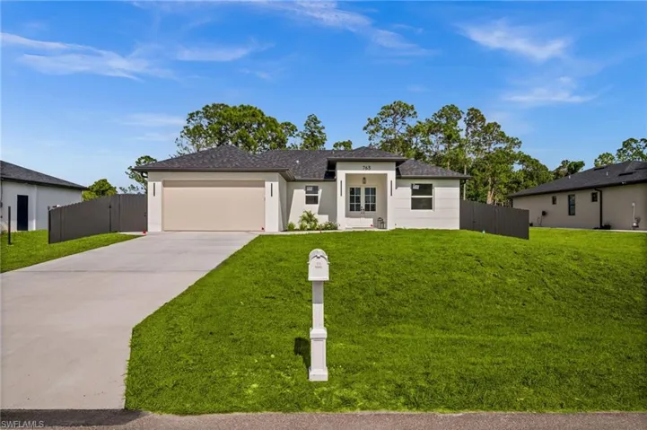 The property features a well-maintained lawn, a paved driveway, and a two-car garage