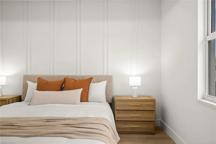 The property includes a bedroom with light-toned wood style flooring, a decorative wall panel, and a window providing natural light