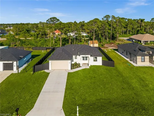 The property features a dark-colored roof, a light-colored exterior, and an attached garage with a light-colored door
