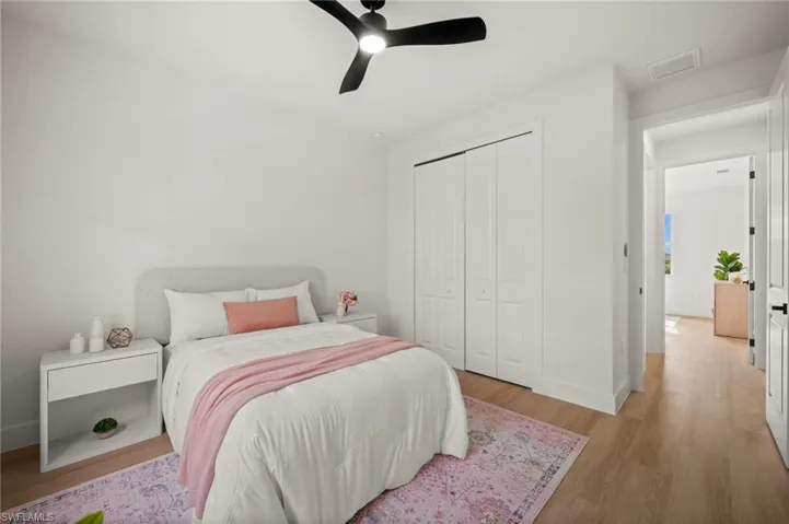 Bedroom featuring light-toned wood style flooring, a ceiling fan, and white bi-fold closet doors