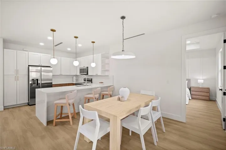 The open-concept kitchen features white cabinetry, stainless steel appliances, and a central island with seating