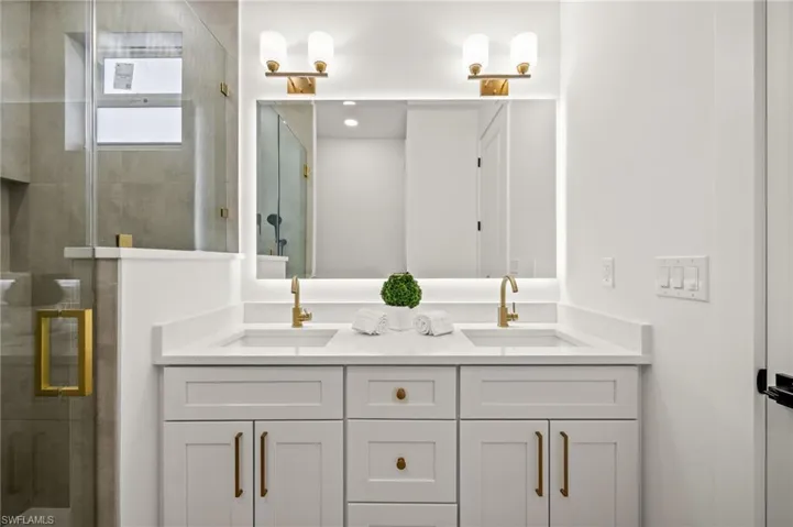 Bathroom featuring a double vanity with white cabinetry, white countertops, and gold-toned faucets
