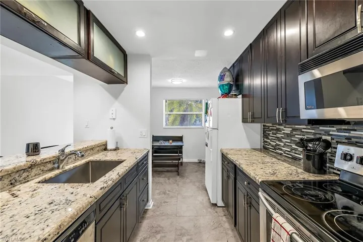 Kitchen featuring stainless steel appliances, light stone countertops, decorative backsplash, and recessed lighting