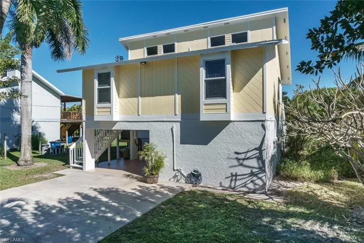 View of front of home with a carport, stairway, driveway, a balcony, and a front yard