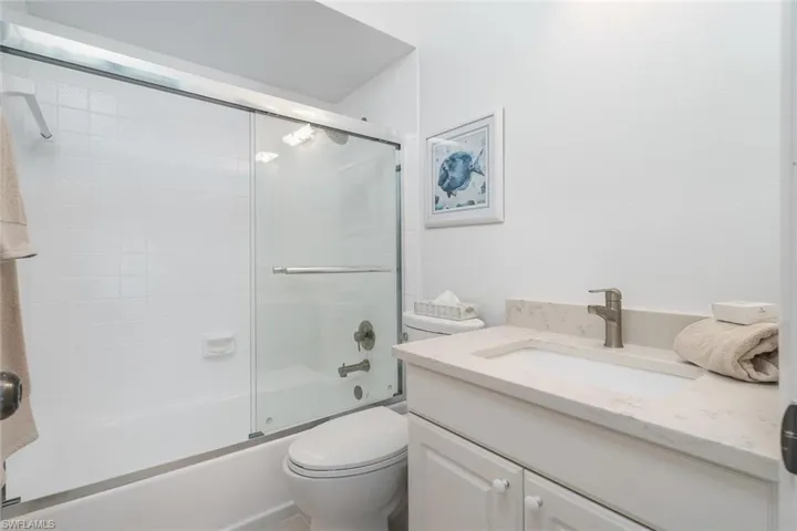 Bathroom featuring bath / shower combo with glass door and vanity