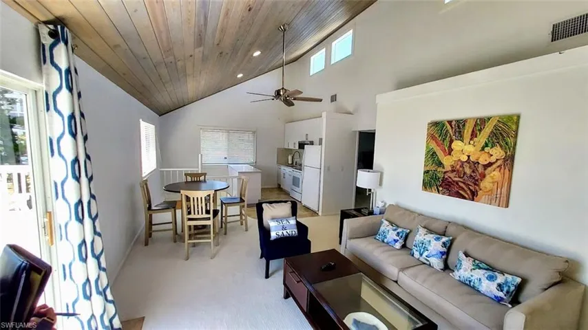 Living room featuring high vaulted ceiling, light colored carpet, a ceiling fan, and wooden ceiling