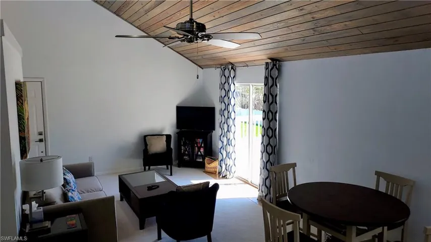 Carpeted living area with wood ceiling, lofted ceiling, and ceiling fan