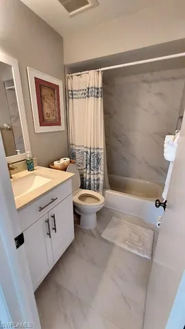 Full bath with shower / bath combo with shower curtain and vanity