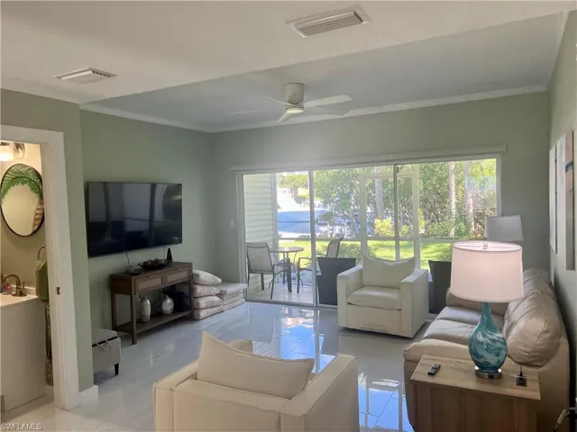 Living area with ornamental molding, plenty of natural light, and ceiling fan