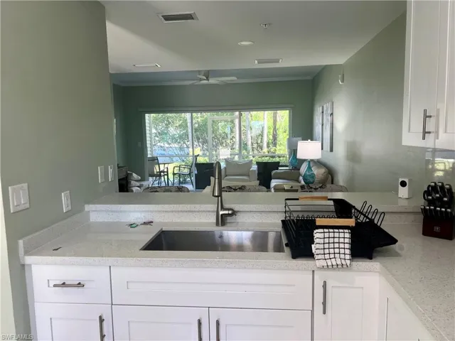 Kitchen with white cabinetry, light stone counters, open floor plan, ceiling fan, and recessed lighting
