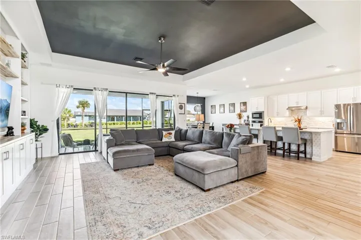 Living room featuring ceiling fan, a raised ceiling, and light hardwood / wood-style flooring