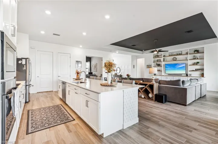 Kitchen with a center island with sink, white cabinets, sink, ceiling fan, and light hardwood / wood-style flooring