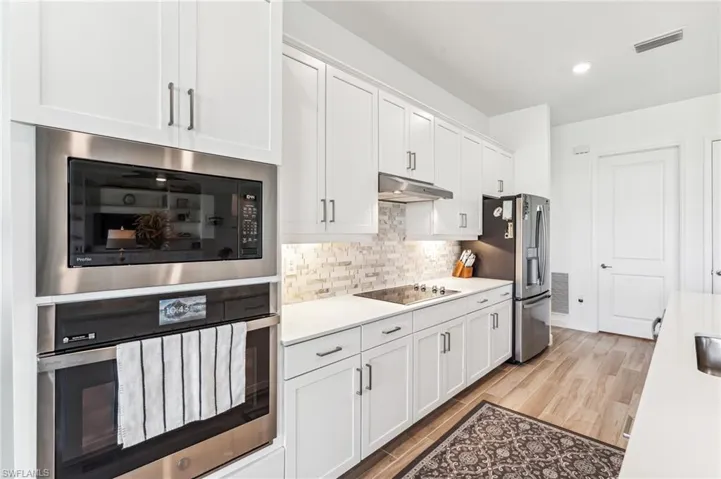Kitchen featuring stainless steel appliances, white cabinets, light hardwood / wood-style flooring, and tasteful backsplash
