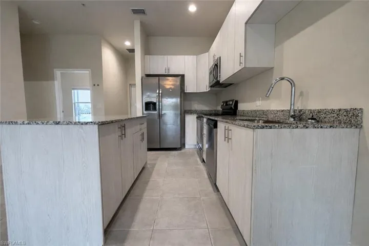 Kitchen featuring dark stone countertops, stainless steel appliances, modern cabinets, recessed lighting, and light brown cabinetry