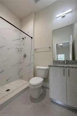 Full bathroom featuring a stall shower, vanity, and light tile patterned floors