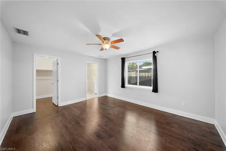 Spacious room featuring wood-finish flooring, a ceiling fan, and a large window